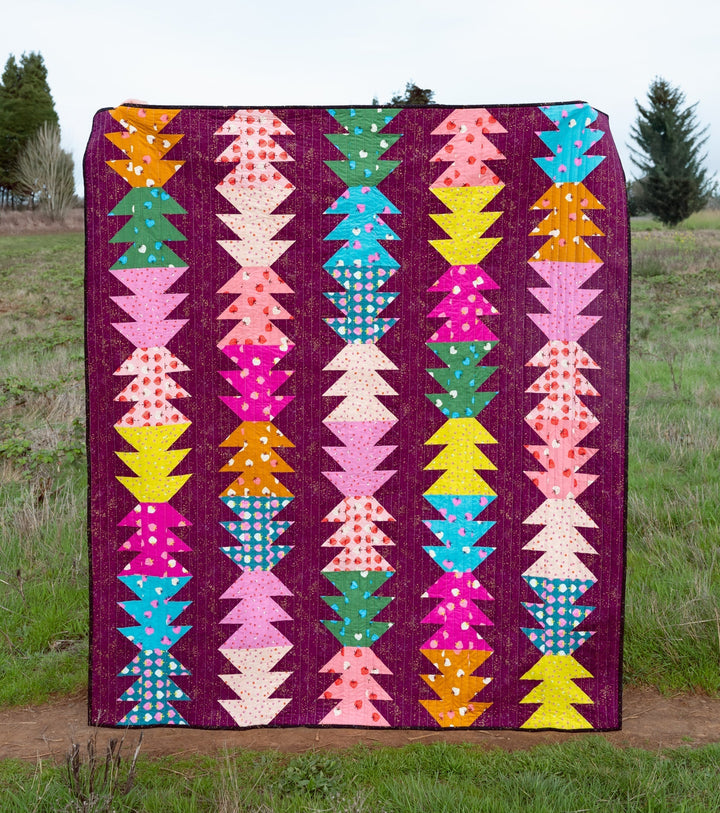 The Piper Quilt made with the Strawberry fabric collection by Ruby Star Society, featuring bold reds, pinks, and contrasting prints in a modern half-square triangle design.